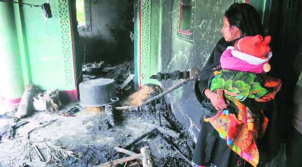 A mother with her child stands in her gutted house at Azizpur village on Monday. (Express Photo by:prashant  Ravi)