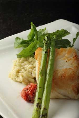 Pan seared Chilean Sea Bass, lemon and herb resotto ,mixed green lettuce, charred broccoli.