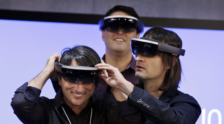 Microsoft's Joe Belfiore, left, smiles as he tries on a "Hololens" device with colleagues Alex Kipman, right, and Terry Myerson following an event demonstrating new features of Windows 10 at the company's headquarters on Wednesday, Jan. 21, 2015, in Redmond, Wash. (Source: AP)