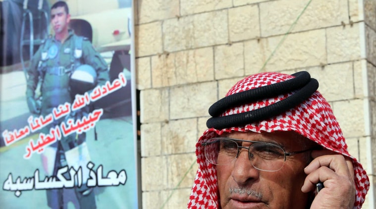 FILE - In this Jan. 3, 2015 file photo, Safi Yousef al-Kaseasbeh, the father of the Jordanian pilot 1st Lt. Mu'ath al-Kaseasbeh, speaks on his mobile phone, while standing by a poster of his son at a gathering of his family in Karak, south of Amman, Jordan. An online video released Tuesday, Feb. 3, 2015 purportedly shows a Jordanian pilot captured by the Islamic State extremist group being burned to death. The Associated Press was not immediately able to confirm the authenticity of the video, which was released on militant websites and bore the logo of the extremist group's al-Furqan media service. (AP Photo/Raad Adayleh, File)