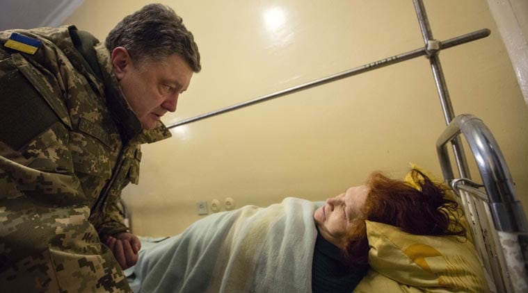 Ukrainian President Petro Poroshenko, left, talks with a wounded victim of an artillery strike in a Kramatorsk hospital, Donetsk region, Ukraine, early Wednesday, Feb. 11, 2015. (AP Photo)
