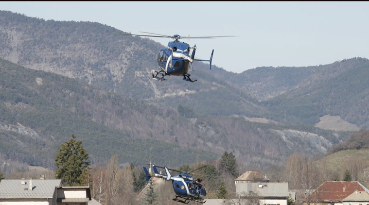 Rescue helicopters land and take off, top, in Seyne-les-Alpes, France, Thursday March 26, 2015. The Germanwings Airbus A320, on a flight from Barcelona, Spain, to Duesseldorf, Germany,inexplicably began to descend from cruising altitude after losing radio contact with ground control and slammed into a remote mountainside in the French Alps on Tuesday, killing all 150 people on board. (AP Photo/Claude Paris)