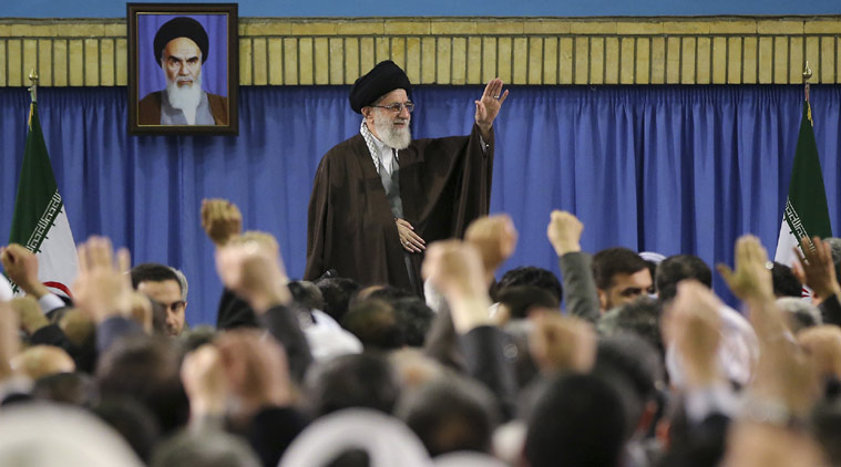 In this picture released by an official website of the office of the Iranian supreme leader, Supreme Leader Ayatollah Ali Khamenei waves while attending a meeting with a group of environmental officials and activists at his residence in Tehran, Iran, Sunday, March, 2015. A portrait of the late revolutionary founder Ayatollah Khomeini hangs in background. (AP Photo/Office of the Iranian Supreme Leader)