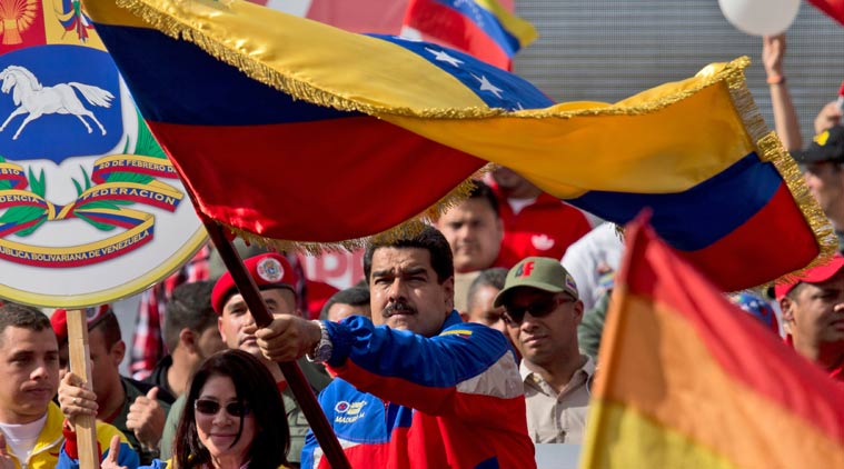 Venezuela's President Nicolas Maduro, center, waves a national flag during a rally in Caracas, Venezuela, Saturday, Feb. 28, 2015. Venezuelans took to the streets of Caracas in dueling demonstrations on Saturday, with one group calling attention to a crackdown on opponents of the government and another showing support for the embattled socialist administration. At left is Venezuela's first lady Cilia Flores. (AP Photo/Fernando Llano)