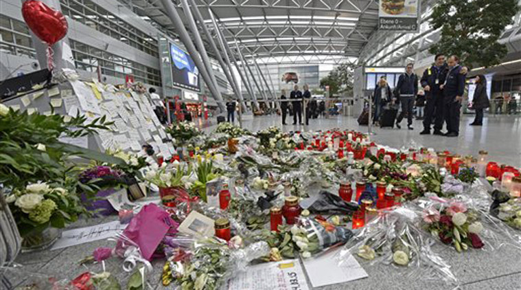 Passengers watch candles and flowers for the victims of the plane crash at the airport in Dusseldorf , Germany. (Source: AP)