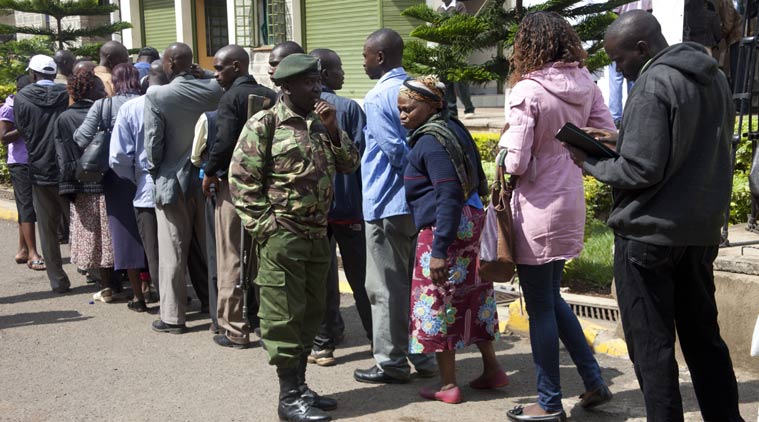 An armed army officer stands guard as relatives wait in a line to view their loved ones who were killed Thursday during an attack on a university, during a ceremony at Chiromo funeral home, Nairobi, Kenya, Monday, April 6, 2015. Al-Shabab gunmen killed scores of people at a university in northeastern Kenya in sectarian violence on Thursday. (AP Photo/Sayyid Azim)