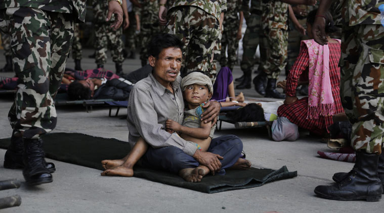 A man sits with a child on his lap as victims of Saturday’s earthquake, wait for ambulances after being evacuated at the airport in Kathmandu, Nepal, Monday, April 27, 2015. The death toll from Nepal's earthquake is expected to rise depended largely on the condition of vulnerable mountain villages that rescue workers were still struggling to reach two days after the disaster. (AP Photo/Altaf Qadri)