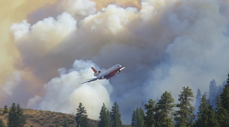 A tanker airplane tanker flies in front of billowing smoke after making a fire retardant drop on a wildfire north of Twisp, Washington. (Source: AP photo)