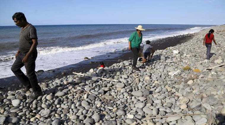 People walk on the beach where a large piece of plane debris was found on Wednesday in Saint-Andre, on the French Indian Ocean island of La Reunion. Reuters Photo