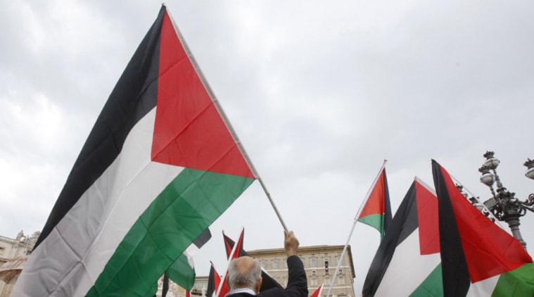 FILE- In this Aug. 3, 2014 file photo, activists wave Palestinian flags as Pope Francis celebrates the Angelus noon prayer from his studio window overlooking St. Peter's square at the Vatican. On Thursday, Sept. 10, 2015, the U.N. General Assembly overwhelmingly approved a resolution allowing the Palestinians and the Holy See to raise their flags at U.N. headquarters, a symbolic step pursued by the Palestinians in their quest for an independent state. (AP Photo/Riccardo De Luca)