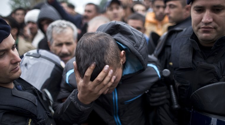 Croatian police officers support an injured man in front of a reception center in Opatovac, Croatia, Tuesday, Sept. 22, 2015. Scuffles have broken out between Croatian police and asylum-seekers after they were barred from entering a newly opened reception center meant to register those seeking sanctuary in Europe. (AP Photo/Marko Drobnjakovic)