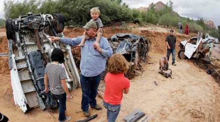 Russ Cook and his family stands next to severely damage vehicles swept away during a flash flood Tuesday, Sept. 15, 2015, in Hildale, Utah. Water swept away the vehicles in the Utah-Arizona border town, killing several people. (AP Photo/Rick Bowmer)