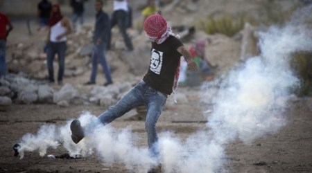 Palestinian kicks a tear gas canister that was fired by Israeli troops during clashes near Ramallah, West Bank, Thursday, Oct. 15, 2015. In the current wave of violence, eight Israelis have been killed in stabbing and shooting attacks, as of Thursday. Thirty-one Palestinians have been killed, including 14 identified by Israel as attackers, and the others in clashes between stone-throwers and Israeli troops. (AP Photo/Majdi Mohammed)