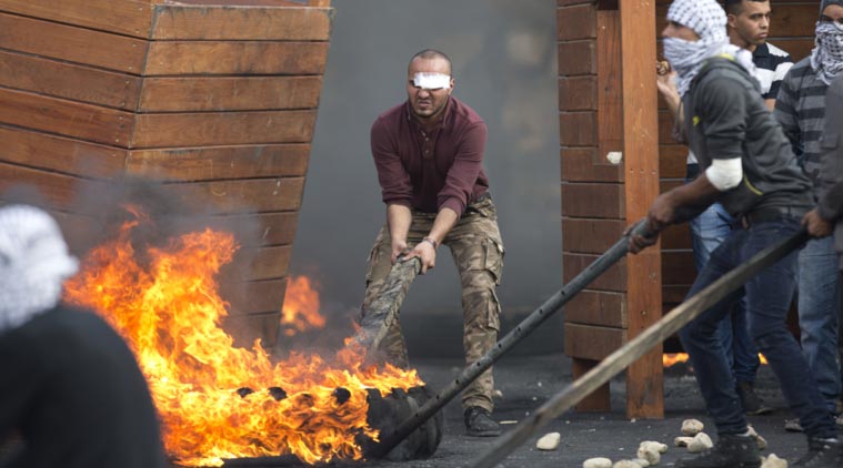 Palestinians push burning tires, during clashes with Israeli troops near Ramallah, West Bank. (Source: AP)