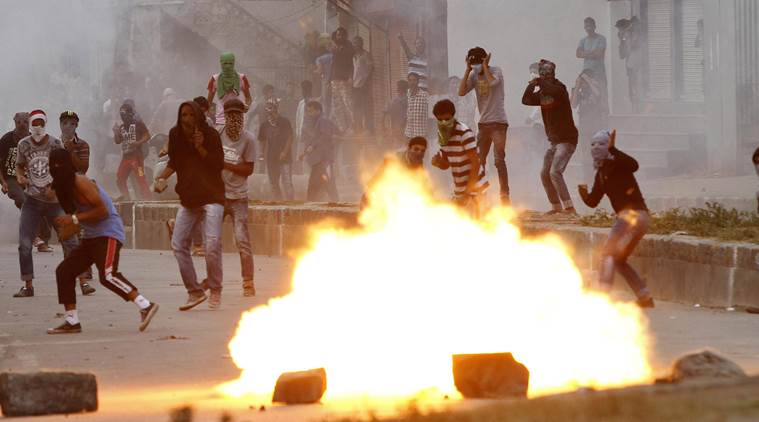 Kashmiri protesters throw stones on government forces as a tear gas shell explodes near them during a protest in Srinagar, Indian controlled Kashmir Sunday, Sept. 20, 2015. Kashmiri separatists called for a strike to protest against the killing of a 3-year-old boy and his father in Indian-controlled Kashmir on Saturday. (AP Photo/Mukhtar Khan)