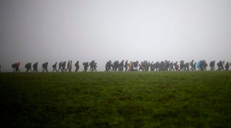 A group of migrants make their way over a meadow after crossing the border between Austria and Germany in Wegscheid near Passau, Germany, Thursday, Oct. 15, 2015. (AP Photo/Matthias Schrader)