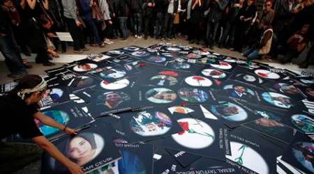 A woman displays the image of one of the victims as thousands of people gather to commemorate the first week anniversary of twin Ankara blasts that claimed 102 lives, in Istanbul, Turkey, Saturday, Oct. 17, 2015. The commemoration started at 10:04am (local), the time the bombs went off last Saturday, and the crowd stood in silence in memory of the deceased victims. The banner reads: " We know the assassin. (AP Photo/Emrah Gurel)