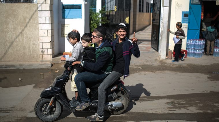 In this Friday, Oct. 30, 2015 photo, a boy gestures to the camera as he and his relatives leave school at Hara Kbira, the main Jewish neighborhood on the Island of Djerba, southern Tunisia. (AP Photo/Mosa'ab Elshamy)