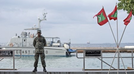 A military person stands guard at a boat jetty next to Maldivian flags erected ahead of Republic Day in Male, Maldives, Thursday, Nov. 5, 2015. Maldives' Parliament voted overwhelmingly on Thursday to impeach the country's vice president, who will be charged with terrorism for plotting to kill the president, a minister said. The president, who was not hurt in the blast, has declared a state of emergency, saying the explosion and subsequent discovery of arms posed a threat to national security. (AP Photo/Sinan Hussain)