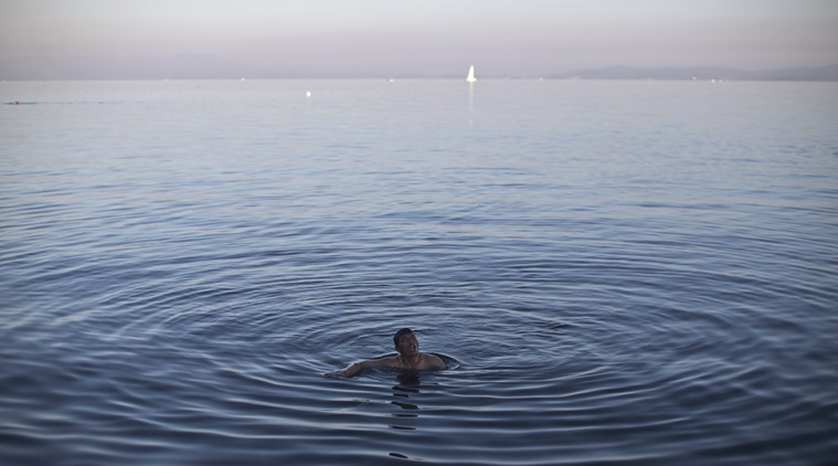 An Afghan man swims in the Aegean sea as he waits for a ferry to transport him to Athens in the port of Mytilene, on the island of Lesbos, Greece, Wednesday, Nov. 4, 2015. Thousands of migrants and refugees are stranded on Lesbos due to a ferry strike that began Monday. (AP Photo/Marko Drobnjakovic)