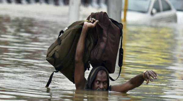 A man moves to safe place from flooded Kotturpuram during heavy rains in Chennai on Wednesday/ PTI