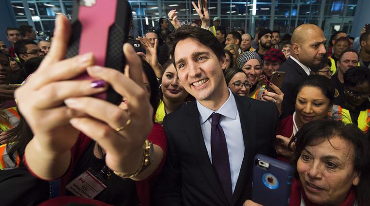 Canadian Prime Minister Justin Trudeau poses for selfies with workers before he greets refugees from Syria at Pearson International airport, in Toronto, on Thursday, Dec. 10, 2015. (The Canadian Press via AP)