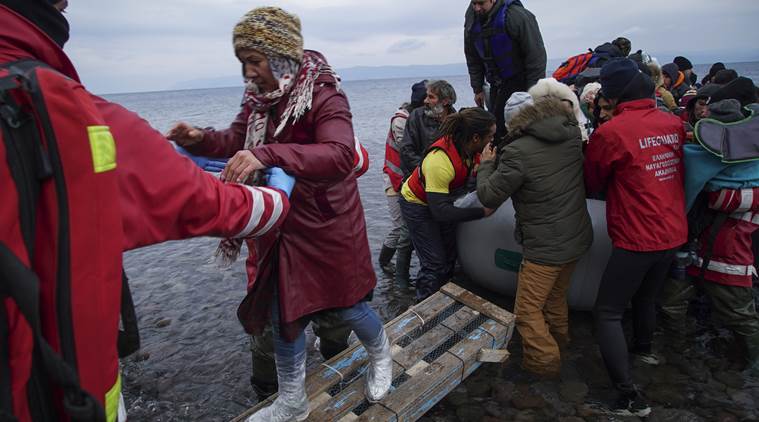 Members of the Greek Red Cross and other volunteers help migrants and refugees to disembark from an inflatable boat after crossing the Aegean sea from Turkey to the Greek island of Lesbos, on Tuesday, Jan. 26, 2016. More than 850,000 people, most fleeing conflict in Syria and Afghanistan, entered Greece by sea in 2015, according to the UNHCR, and already in 2016, some 35,455 people have arrived despite plunging winter temperatures. (AP Photo/Mstyslav Chernov)