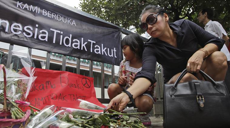 A woman lays flower outside the Starbucks cafe where Thursday's attack took place in Jakarta, Indonesia, Saturday, Jan. 16, 2016. Indonesian police said Saturday they have arrested a number of people suspected of links to the audacious attacks by suicide bombers and gunmen on Thursday in central Jakarta, the first major assault by militants in Indonesia since 2009. Writings on the banner read "Indonesia is not afraid." (AP Photo/Tatan Syuflana)