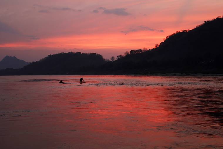 In this March 4, 2011, file photo, men ride in a boat across the Mekong River in Luang Prabang, Laos. It is officially described as the best-preserved city in Southeast Asia, a bygone seat of kings tucked into a remote river valley of Laos. Luang Prabang weaves a never-never land spell on many a visitor with its tapestry of French colonial villas and Buddhist temples draped in a languid atmosphere. (AP Photo/Jacquelyn Martin, File)