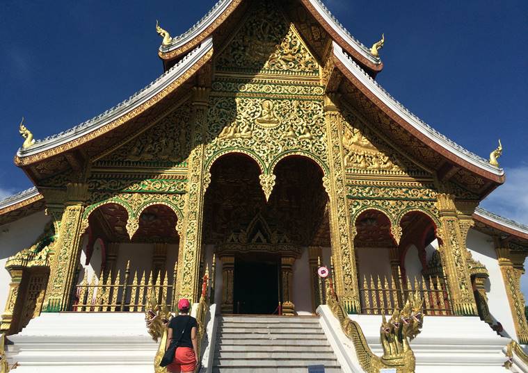In this Sept. 8, 2014 photo, a tourist visits the Haw Pha Bang temple in the grounds of the Palace Museum in Luang Prabang, Laos. It is officially described as the best-preserved city in Southeast Asia, a bygone seat of kings tucked into a remote river valley of Laos. Luang Prabang weaves a never-never land spell on many a visitor with its tapestry of French colonial villas and Buddhist temples draped in a languid atmosphere. (AP Photo/Mark Baker)