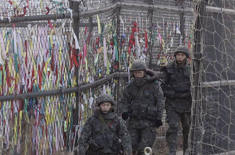 South Korean army soldiers patrol by ribbons, wishing for the reunification of the two Koreas, attached on the barbed-wire fence in Paju, near the border with North Korea. (AP Photo/Ahn Young-joon)