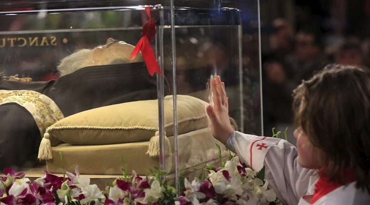 An altar boy touches the glass where the exhumed body of the mystic saint Padre Pio lies in the Catholic church of San Lorenzo fuori le Mura in Rome. (Photo: Reuters)