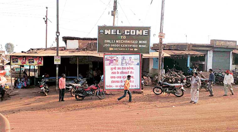 A man walks past a poster showing Dr Saibal Jana being led by a policeman, at one of Dalli-Rajhara’s three chowks. (Express Photo)