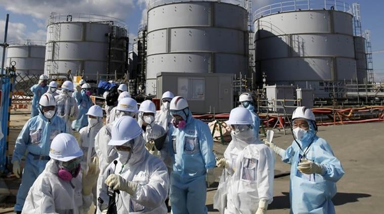 Members of the media, wearing protective suits and masks, walk after receiving a briefing from Tokyo Electric Power Co. (TEPCO) employees (in blue) in front of storage tanks for radioactive water at TEPCO's tsunami-crippled Fukushima Daiichi nuclear power plant in Okuma town, Fukushima prefecture, Japan in this February 10, 2016 file photo. The robots sent in to find highly radioactive fuel at Fukushima's nuclear reactors have "died"; a subterranean "ice wall" around the crippled plant meant to stop groundwater from becoming contaminated has yet to be finished. And authorities still don't how to dispose of highly radioactive water stored in an ever mounting number of tanks around the site. REUTERS/Toru Hanai/Files