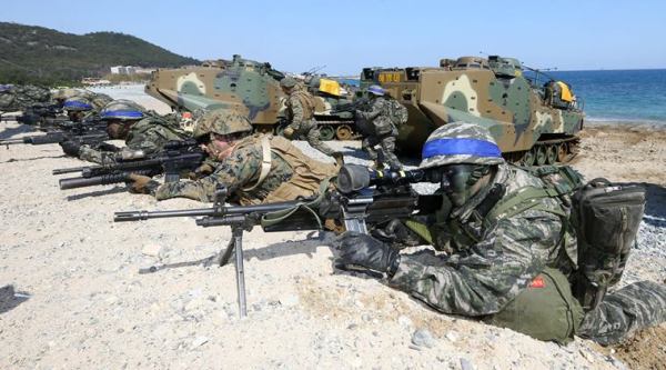 South Korean Marines, wearing blue headbands on their helmets, and U.S. Marines take positions after landing on the beach during the joint military combined amphibious exercise, called Ssangyong, part of the Key Resolve and Foal Eagle military exercises, in Pohang, South Korea, Saturday, March 12, 2016.  North Korea said Saturday its military is ready to pre-emptively attack and "liberate" the South in its latest outburst against the annual joint military drills by the United States and South Korea. (Kim Jun-bum/Yonhap via AP) KOREA OUT
