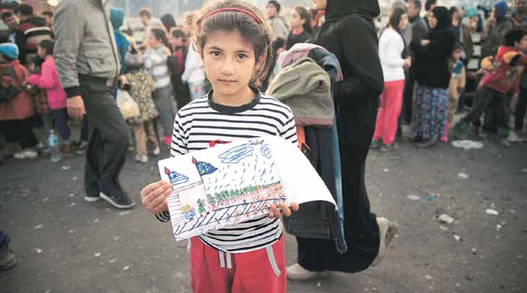 Shaharzad Hassan, 8, whose family fled Aleppo, poses with a drawing she made at an overcrowded refugee camp on the Greece-Macedonia border last week. (Source: AP)