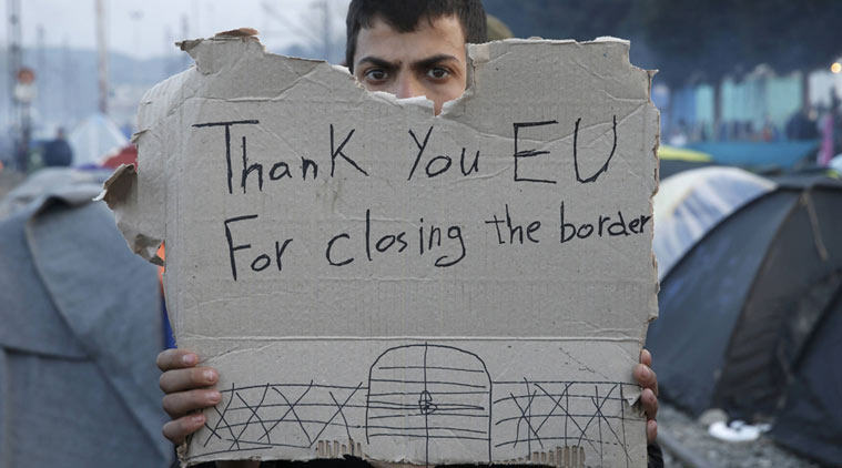 A refguee holds a message, “Thank you EU for closing the border” during a protest asking for the opening of borders at a makeshift camp at the Greek-Macedonian border near the village of Idomeni, Greece, March 18, 2016. (REUTERS)
