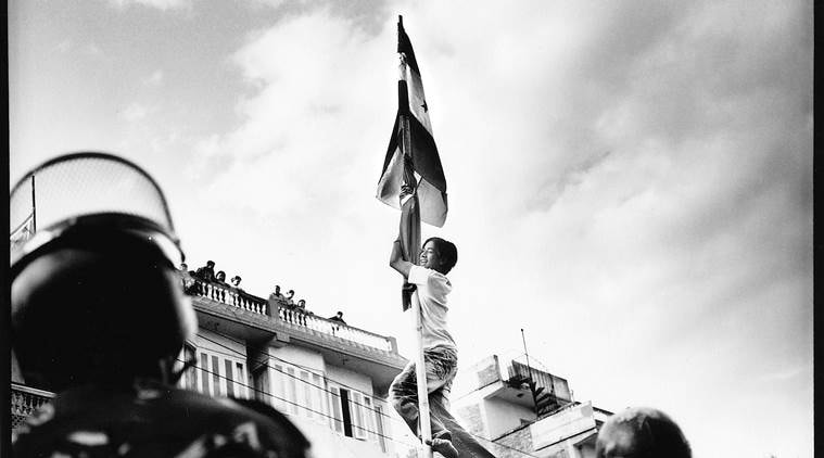 A Demonstrator climbs a flag pole and hangs over police lines at a mass rally aimed at pressuring King Gyanendra to step down in Chabahil on the Kathmandu ring-road.