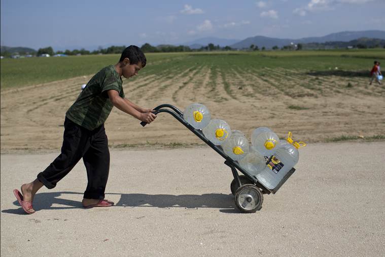 A boy pushes a  barrow with water at the northern Greek border point of Idomeni, Greece, on Monday, May 9, 2016. About 54,000 refugees and migrants are currently stranded in Greece as 10,000 are camped in Idomeni, after the European Union and Turkey reached a deal designed to stem the flow of refugees into Europes prosperous heartland. (AP Photo/Petros Giannakouris)