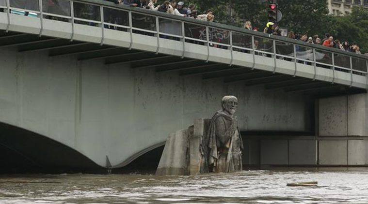 People stand on the Pont de l'Alma as they look at the Zouave statue covered by the rising waters from the Seine River after days of rainy weather in Paris, France. Reuters