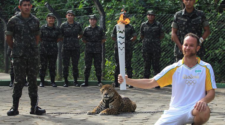 Brazilian physiotherapist Igor Simoes Andrade poses for picture next to jaguar Juma as he takes part in the Olympic Flame torch relay in Manaus
