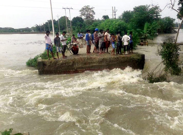 Villagers watch land erosion in Kishanganj district, Bihar on Tuesday. (Source: PTI)