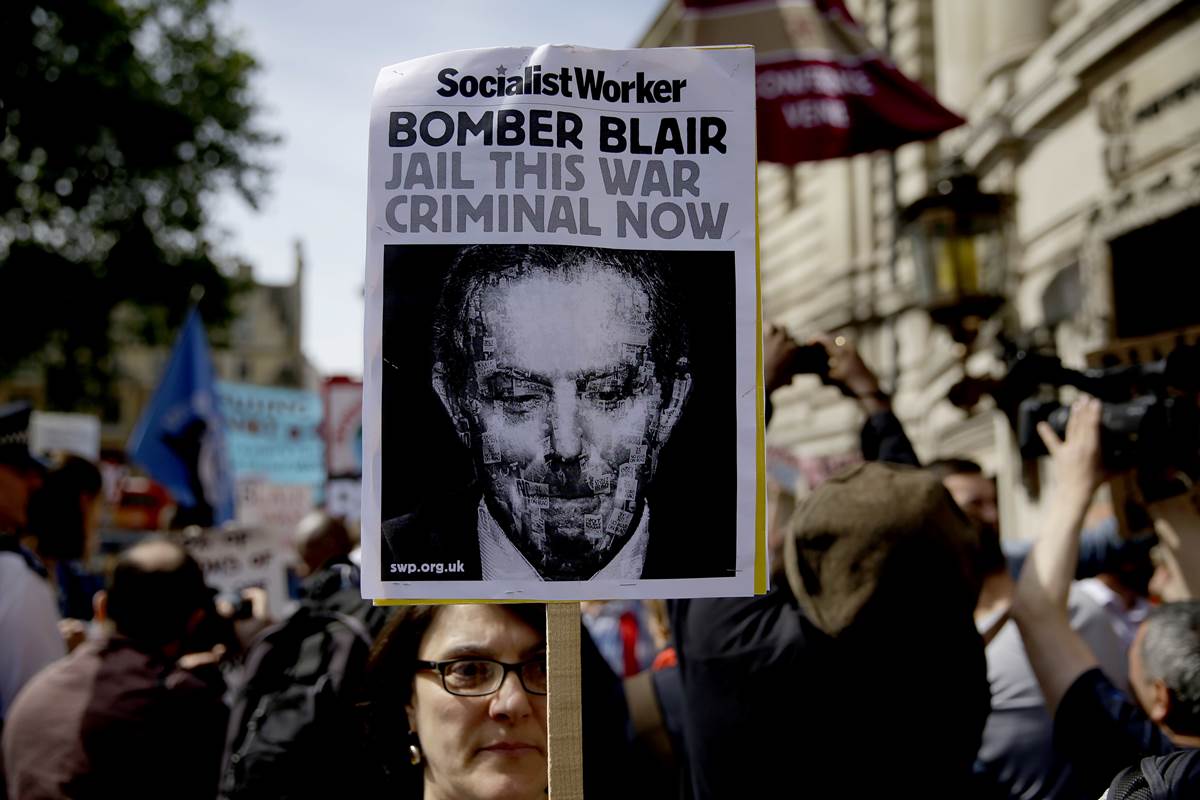 A protester holds up a placard during a demonstration outside the Queen Elizabeth II Conference Centre in London, before the publication of the Chilcot report into the Iraq war, Wednesday, July 6, 2016. The Iraq war was mounted on flawed intelligence, was executed with "wholly inadequate" planning, and ended "a long way from success," according to a damning report released Wednesday by the head of Britain's Iraq War inquiry. (AP Photo/Matt Dunham)