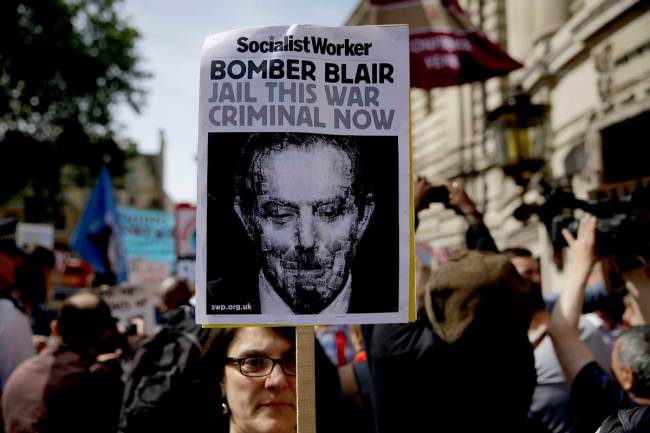 A protester holds up a placard during a demonstration outside the Queen Elizabeth II Conference Centre in London, before the publication of the Chilcot report into the Iraq war, Wednesday, July 6, 2016. The Iraq war was mounted on flawed intelligence, was executed with "wholly inadequate" planning, and ended "a long way from success," according to a damning report released Wednesday by the head of Britain's Iraq War inquiry. (AP Photo/Matt Dunham)