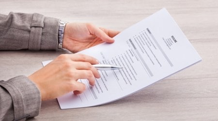 Close-up Of A Businesswoman At Desk Holding Resume