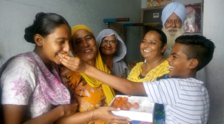 Family of Gurdip Singh exchanging sweets after his phone call from Indonesia on Friday morning (Express photo)