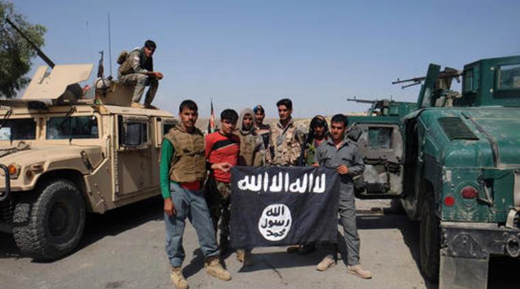 FILE - in this Monday, Aug. 1, 2016 photo, Afghan police pose for a photograph with an Islamic State flag after an operation in the Kot district of Jalalabad province east of Kabul, Afghanistan. The Islamic State group, which has been building a presence in Afghanistan for more than a year, has established a recruitment and training camp in a restive southern province bordering Pakistan. (AP Photo/Melad Hamedi, file)