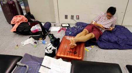 A passenger plays a game at Narita international airport in Narita, east of Tokyo, Tuesday, Aug. 9, 2016. He stayed one night in airport lobby. More than 1,000 people spent the night at Narita airport outside Tokyo because of the computer shutdown that halted Delta Air Lines flights worldwide. (AP Photo/Shizuo Kambayashi)