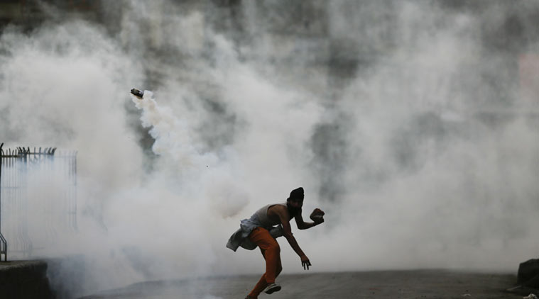 A Kashmiri protester throws a tear smoke shell on government forces on Monday. (AP Photo)