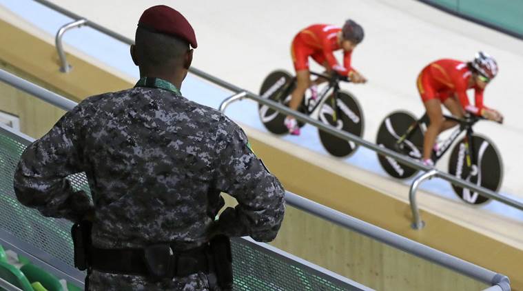 A police officer watches as members of the Chinese women's track cycling team round the track during a training session inside the Rio Olympic Velodrome in advance of the 2016 Olympic Games in Rio de Janeiro, Brazil, Thursday, Aug. 4, 2016. (AP Photo/Patrick Semansky)
